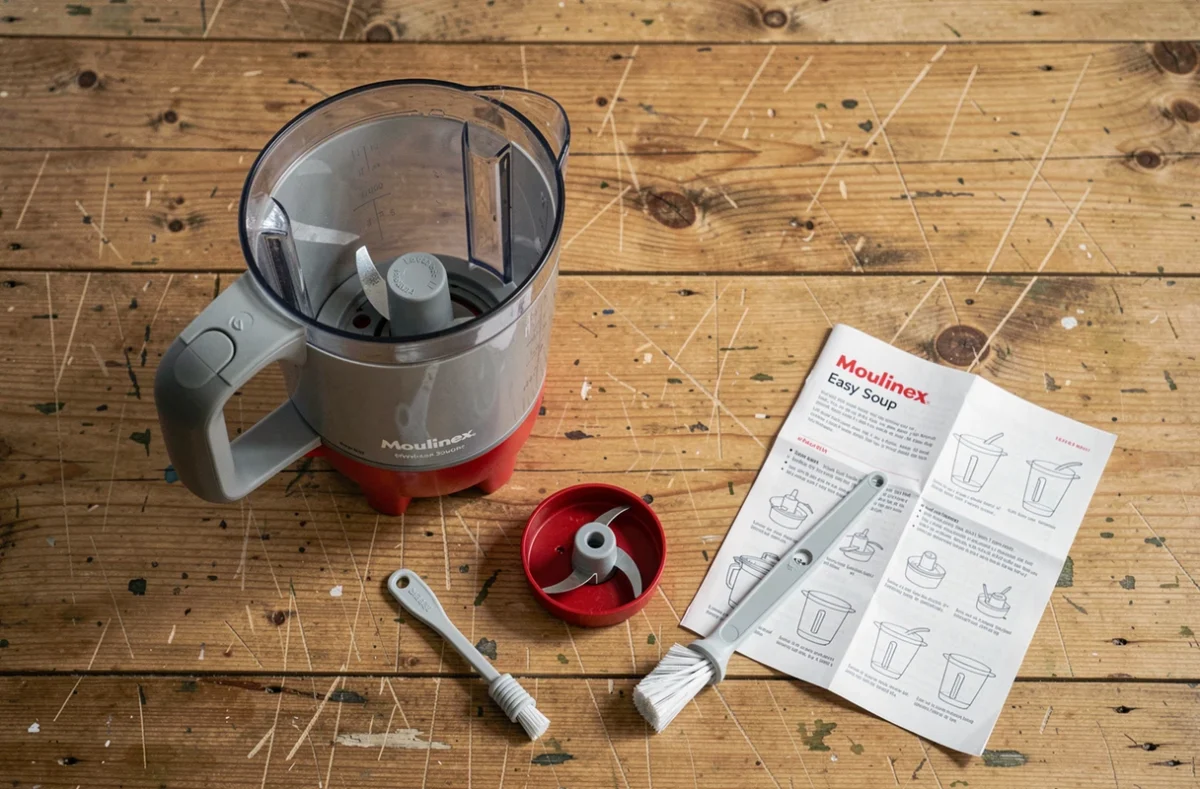 Démontage du blender Moulinex Easy Soup avec lame et brosse de nettoyage posées sur une table en bois